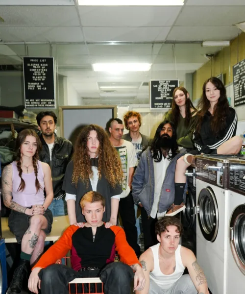 Group of young adult standing close together in a launderette