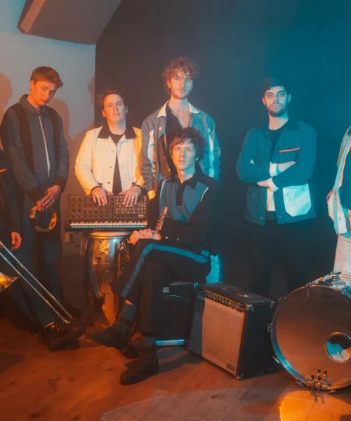 Group of men and their instruments in front of a dark wall